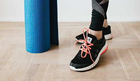 women wearing sneakers next to a rolled up yoga mat