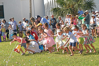 children wearing Easter attire racing to find hidden eggs
