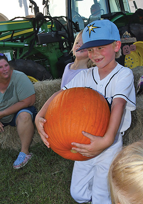 child carrying a large pumpkin