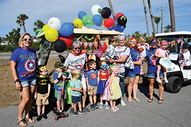 group of adults and children wearing costumes and standing beside decorated golf carts